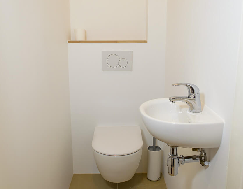 Hangend toilet met inbouw reservoir en een wastafel in kleine wc ruimte